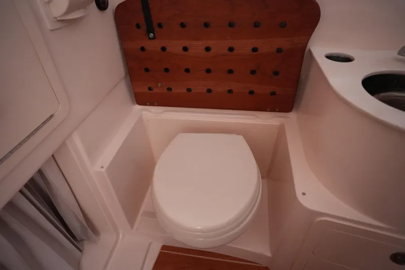 Slide: The Image of 2023 Grady-White Canyon 336 boat bathroom with toilet and wooden panel. - 37