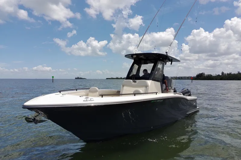 Slide: The Image of 2026 Scout 260 LXF boat on calm water under a partly cloudy sky. - 1