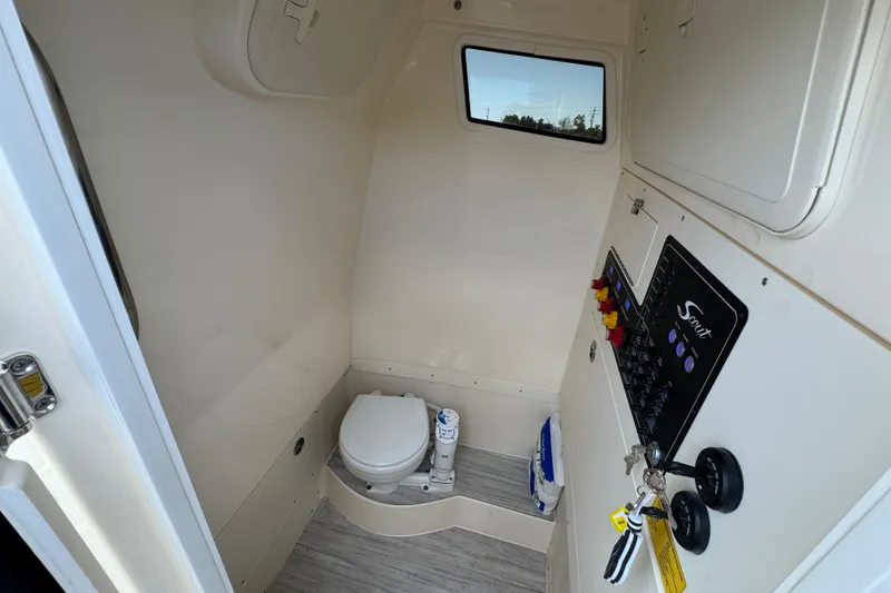 Slide: The Image of Interior of 2026 Scout 260 LXF boat featuring a compact marine toilet and control panel. - 16