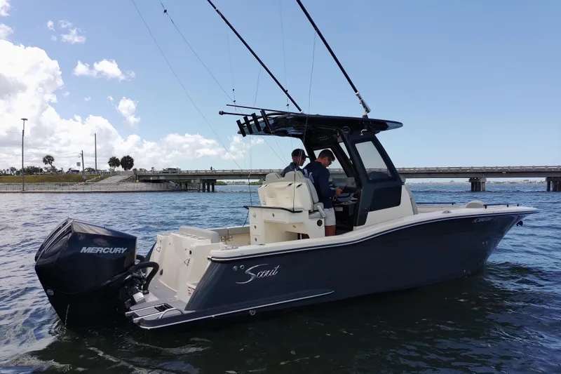 Slide: The Image of 2026 Scout 260 LXF boat on water with Mercury engine, bridge in background. - 2