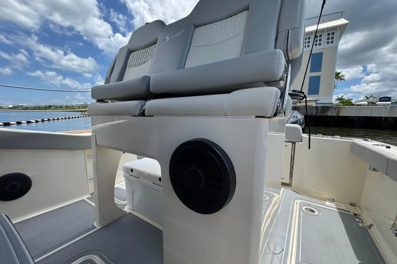 Slide: The Image of 2026 Scout 260 LXF boat interior with cushioned seating and speaker, dockside view. - 24