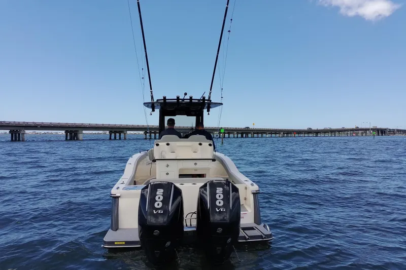Slide: The Image of 2026 Scout 260 LXF boat with dual engines on open water near a bridge. - 4