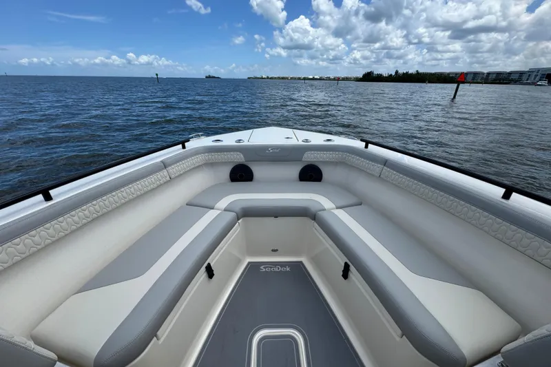 Slide: The Image of 2026 Scout 260 LXF boat interior with cushioned seating, on a calm ocean under a cloudy sky. - 7