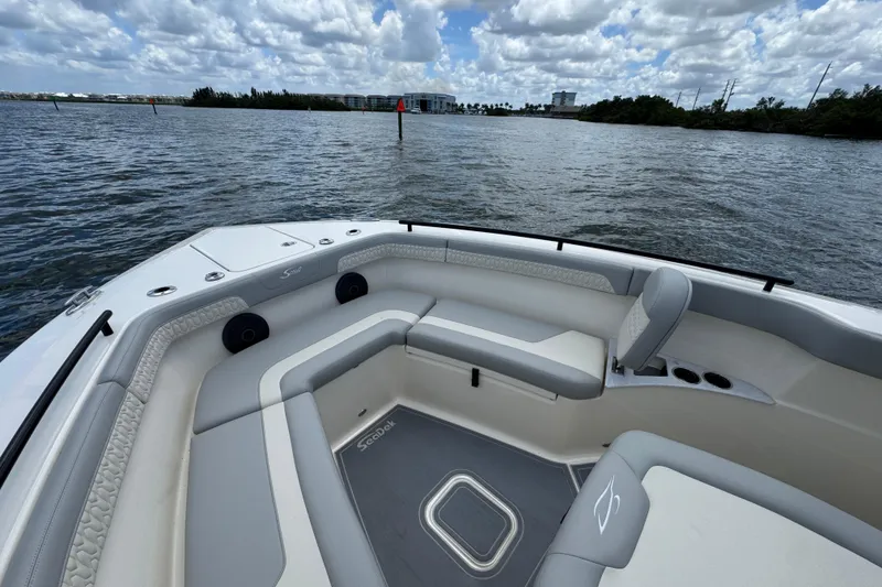 Slide: The Image of 2026 Scout 260 LXF boat interior with seating, on a calm waterway under cloudy skies. - 8