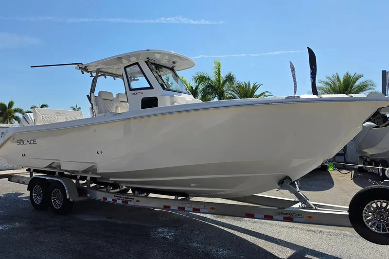 Slide: The Image of 2026 Solace 30CS boat on trailer, displayed outdoors with palm trees in background. - 5