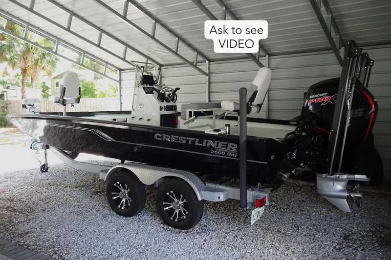Slide: The Image of 2023 Crestliner 2000 Bay boat in a covered storage area with trailer. - 1