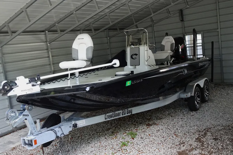 Slide: The Image of 2023 Crestliner 2000 Bay boat in a metal storage shed, featuring a sleek black design. - 3