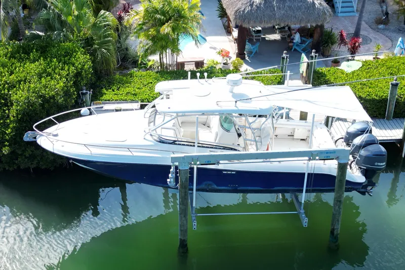 Slide: The Image of 2005 Hydra-Sports Vector 3300 VX boat docked, surrounded by lush greenery and a thatched-roof hut. - 7