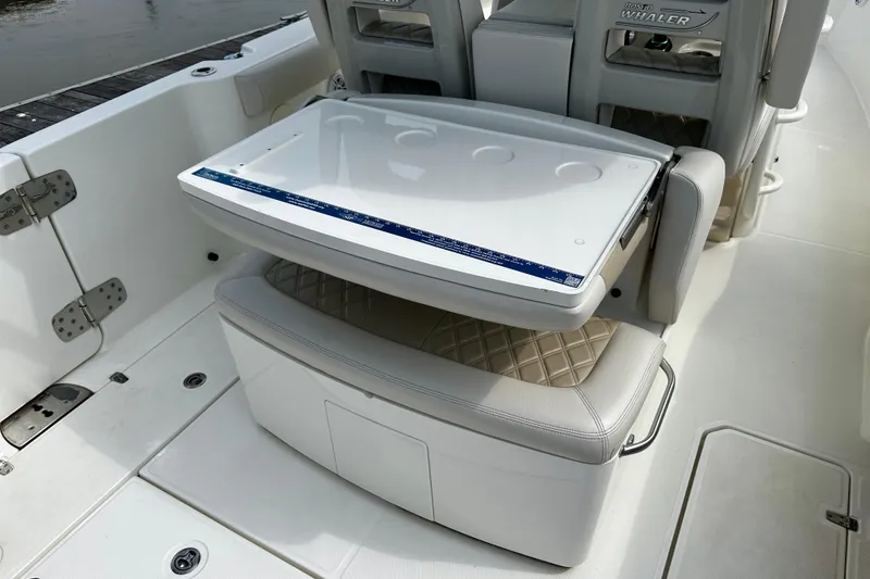 Slide: The Image of 2019 Boston Whaler 330 Outrage boat interior with foldable seat and storage compartment. - 15