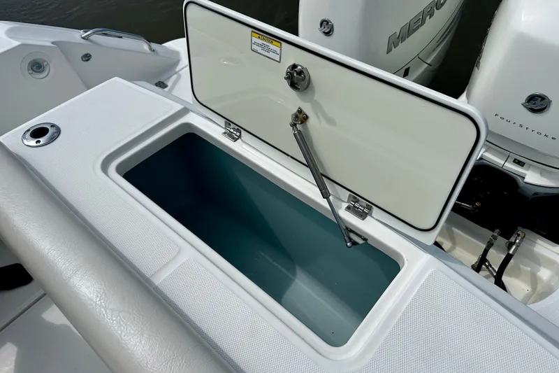 Slide: The Image of Open storage compartment on a 2019 Boston Whaler 330 Outrage boat, with Mercury engines visible. - 24