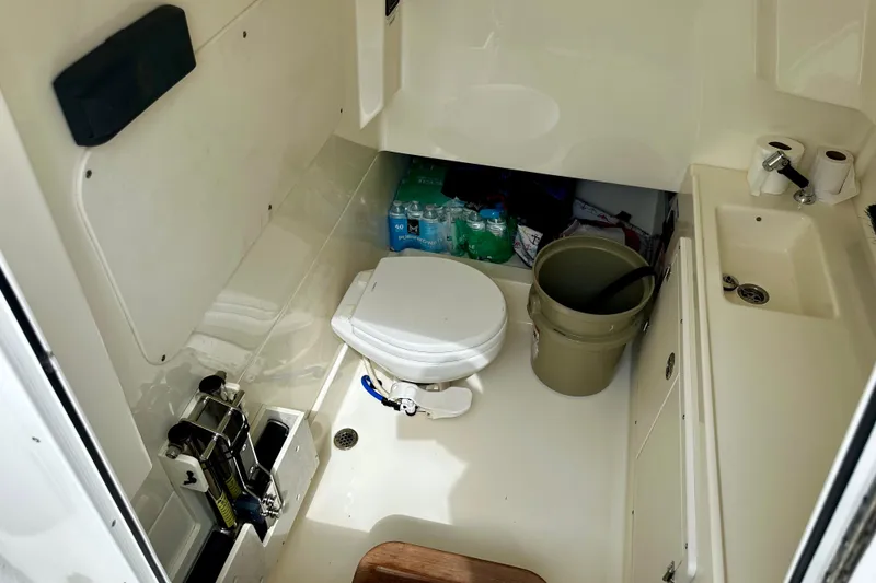 Slide: The Image of Interior of 2019 Boston Whaler 330 Outrage boat bathroom with toilet and sink. - 26