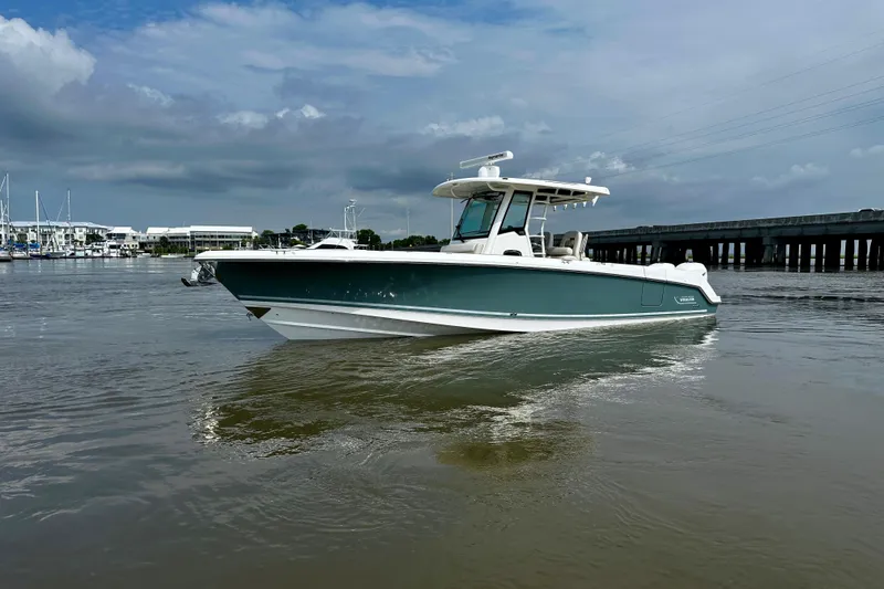 Slide: The Image of 2019 Boston Whaler 330 Outrage boat cruising on a calm river under a cloudy sky. - 6
