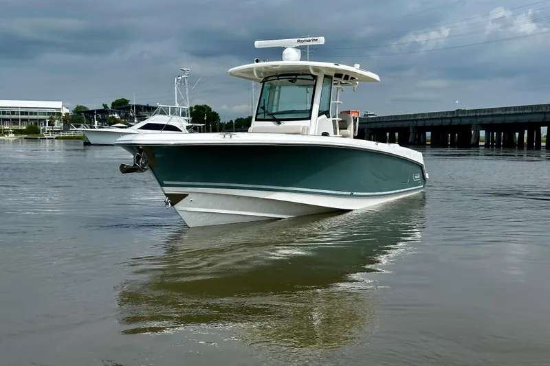 Slide: The Image of 2019 Boston Whaler 330 Outrage boat on calm water near a bridge. - 7