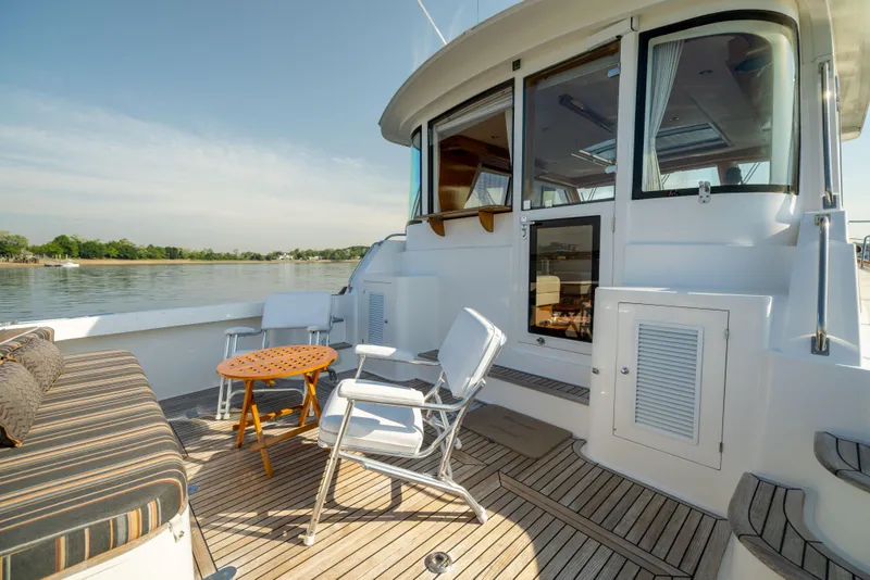 Slide: The Image of 2008 Grand Banks 45 Eastbay SX yacht deck with seating and table, overlooking calm waters. - 12