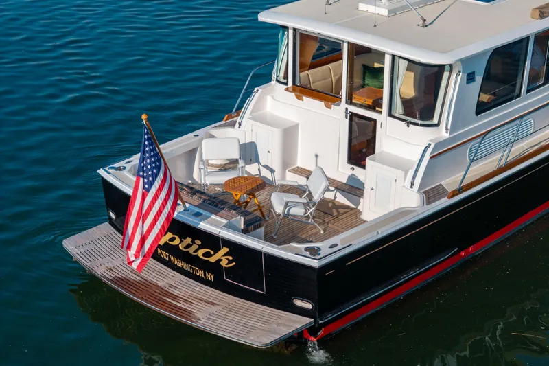 Slide: The Image of 2008 Grand Banks 45 Eastbay SX yacht with American flag, docked in calm waters. - 2