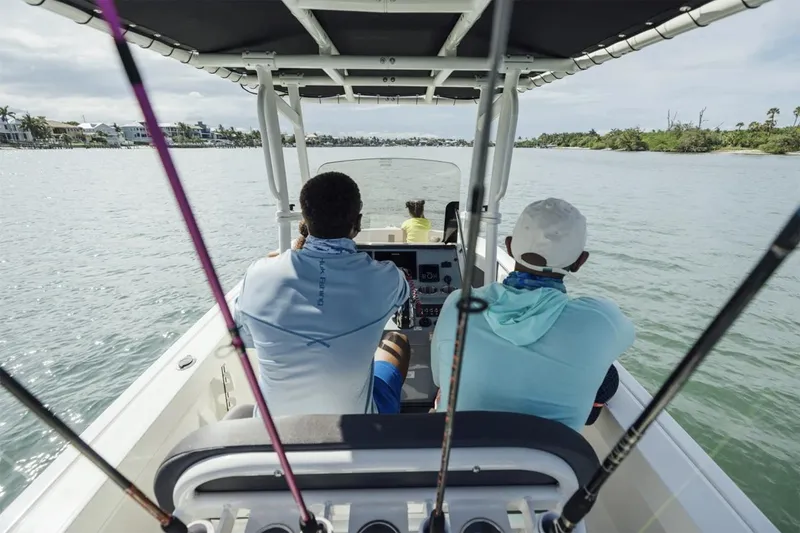 Slide: The Image of Manufacturer Provided Image: 2025 Bayliner Trophy T20CC boat with passengers and fishing rods on a calm waterway. - 3