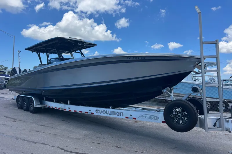 The Image of 2022 Nor-Tech 390 Sport Center Console boat on trailer under blue sky. - 0