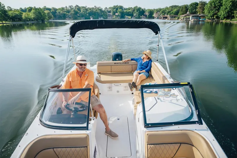 Slide: The Image of Manufacturer Provided Image: 2025 Bayliner D22 boat cruising on a serene lake with two passengers enjoying the ride. - 2