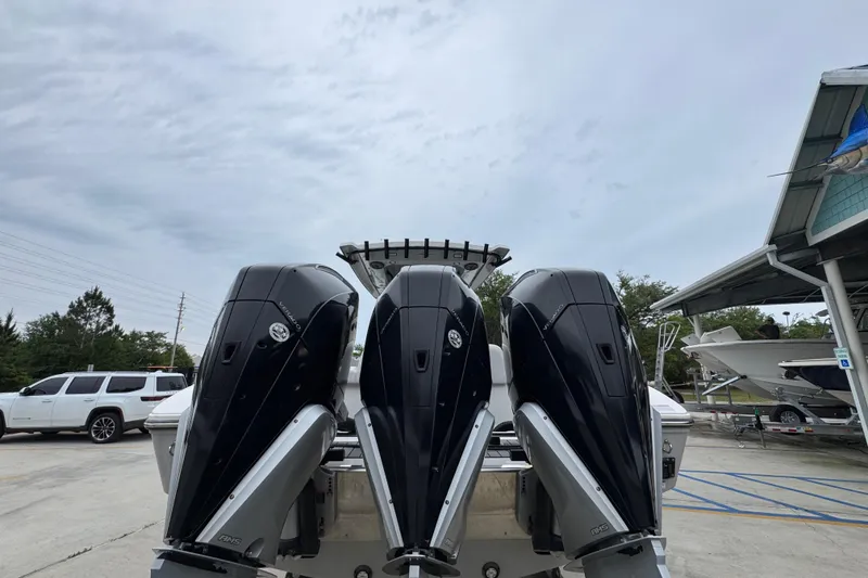 Slide: The Image of 2021 Fountain 34 Center Console with triple outboard engines at a marina. - 12