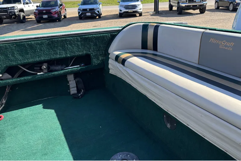 Slide: The Image of Interior of a 2003 MirroCraft 1737 Holiday boat with green carpet and striped seating. - 12