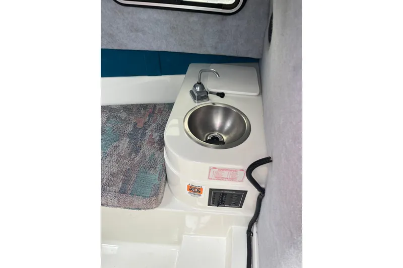 Slide: The Image of Interior of 1995 Celebrity 2500 Fish Hawk boat featuring a compact sink and control panel. - 20
