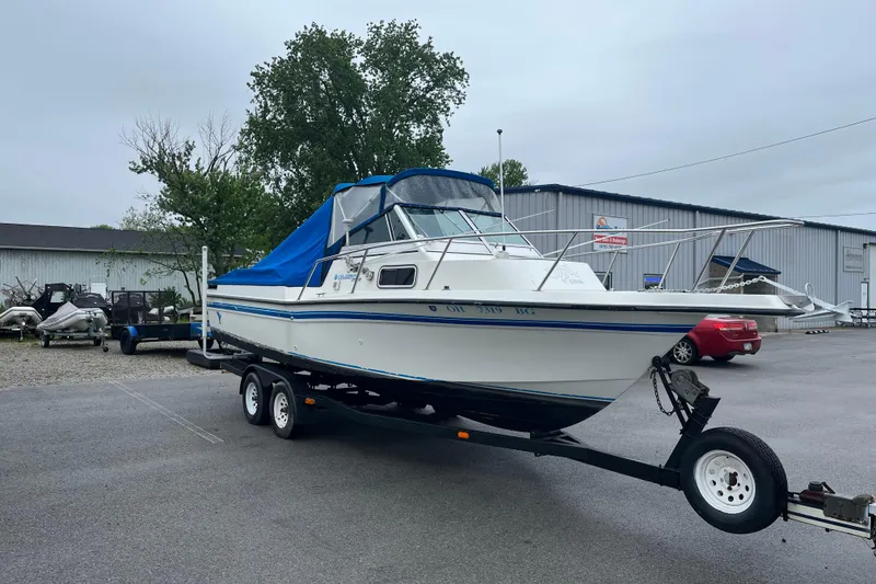 Slide: The Image of 1995 Celebrity 2500 Fish Hawk boat on trailer, blue cover, parked outdoors. - 4