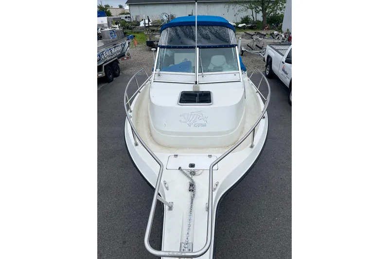 Slide: The Image of 1995 Celebrity 2500 Fish Hawk boat with blue canopy, parked on pavement. - 5