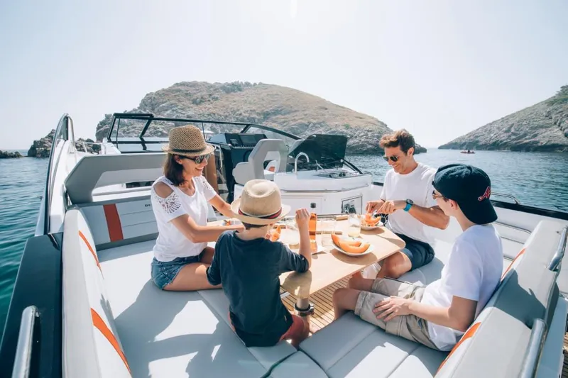 Slide: The Image of Family enjoying a meal on a 2024 Beneteau Flyer 10 boat in a scenic bay. - 27