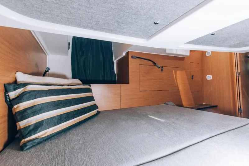 Slide: The Image of 2024 Beneteau Flyer 10 cabin interior with bed and striped pillow. - 37