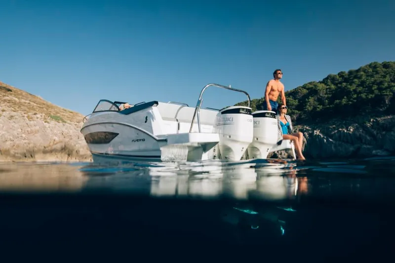 Slide: The Image of 2024 Beneteau Flyer 10 boat with two people, anchored near rocky shore. - 9