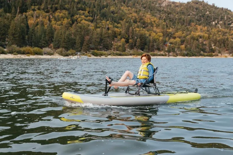 Slide: The Image of Person enjoying a ride on a 2023 Hobie iTrek 9 Ultralight inflatable kayak on a lake. - 1
