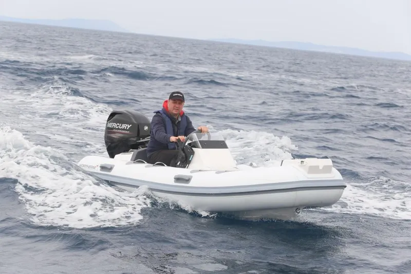 Slide: The Image of Man driving 2024 Northstar Axis 3.1 inflatable boat on open water. - 1