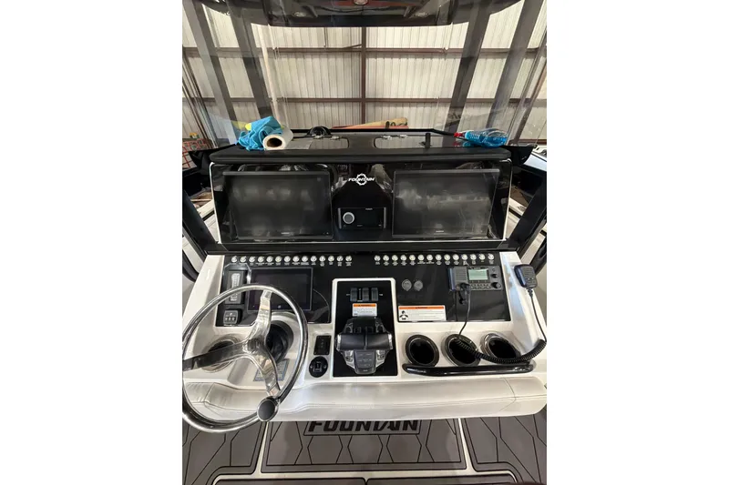 Slide: The Image of 2022 Fountain 34 Center Console boat dashboard with steering wheel and electronic controls. - 10