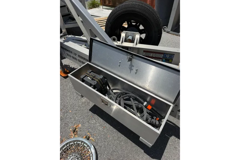 Slide: The Image of Open storage compartment on a 2022 Fountain 34 Center Console trailer, containing cables and equipment. - 24