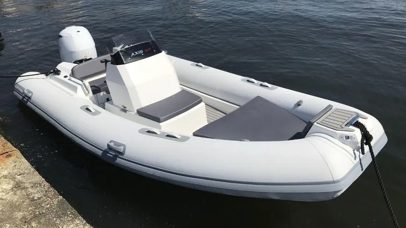 Slide: The Image of 2024 Northstar Axis 4.8 inflatable boat docked on calm water. - 4