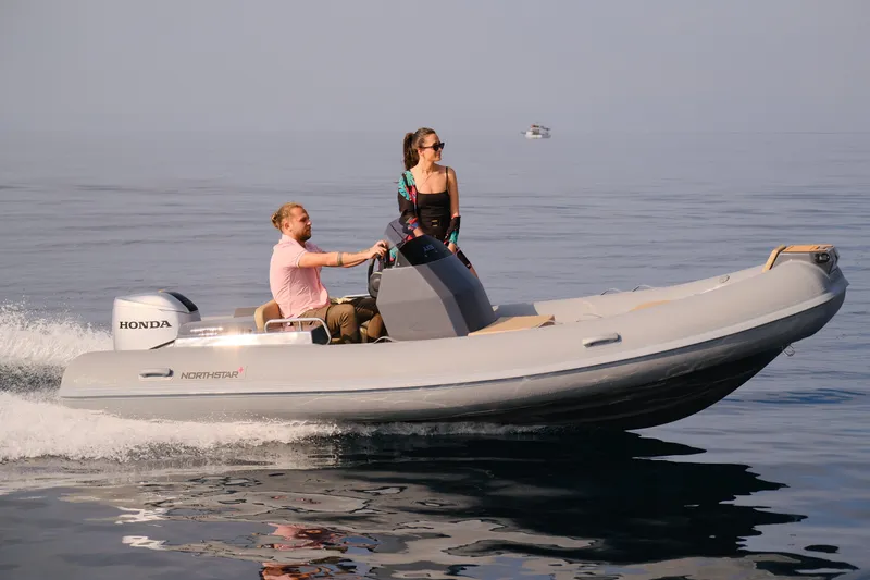 Slide: The Image of 2024 Northstar Axis 4.8 boat cruising on calm water with two passengers. - 7
