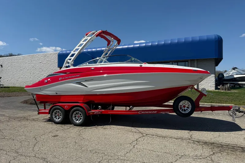 The Image of 2025 Crownline Eclipse E235 boat on a red trailer, parked outdoors. - 1
