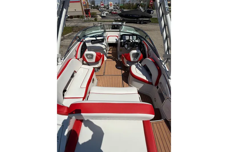 Slide: The Image of 2025 Crownline Eclipse E235 boat interior with red and white seating, wood flooring, and steering console. - 10