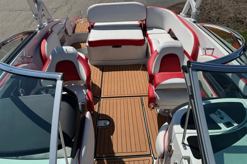 Slide: The Image of 2025 Crownline Eclipse E235 boat interior with red and white seating, wood-style flooring. - 6