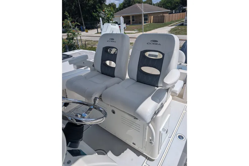 Slide: The Image of 2020 Cobia 262 Center Console boat seats with steering wheel, outdoor setting. - 5
