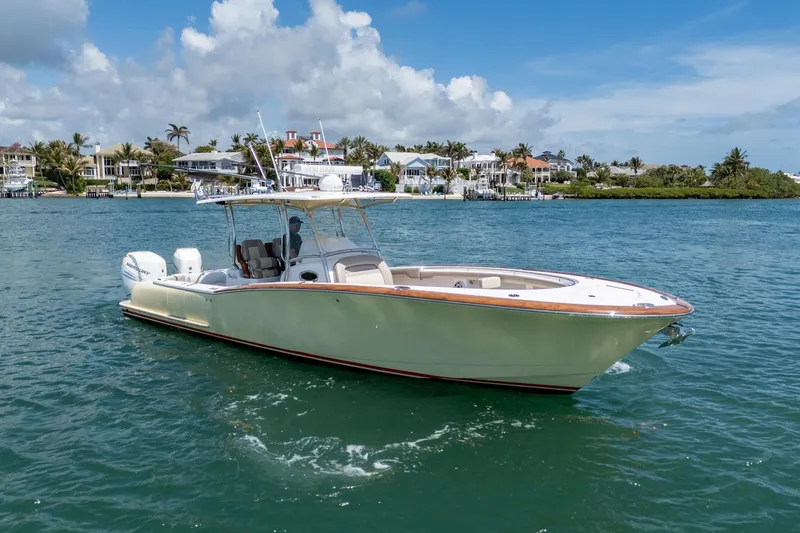 Slide: The Image of 2020 Mag Bay 33 CC boat cruising on a sunny day near waterfront homes. - 11