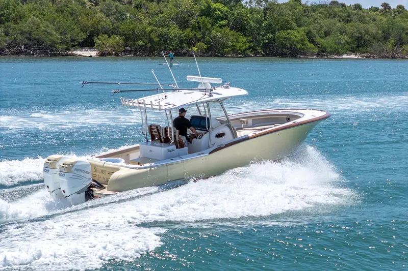 Slide: The Image of 2020 Mag Bay 33 CC boat cruising on blue water near lush green shoreline. - 22
