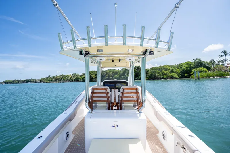 Slide: The Image of 2020 Mag Bay 33 CC boat on serene water with lush greenery backdrop. - 24