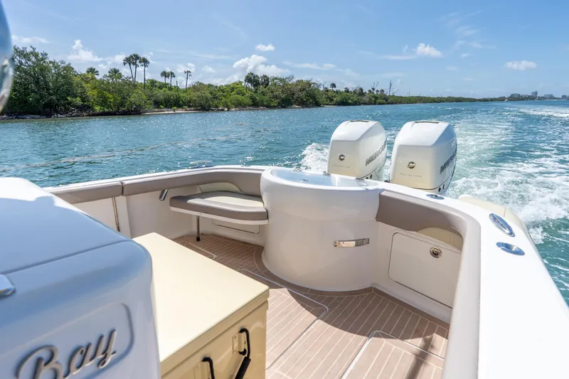 Slide: The Image of 2020 Mag Bay 33 CC boat cruising on a scenic waterway with twin engines. - 33