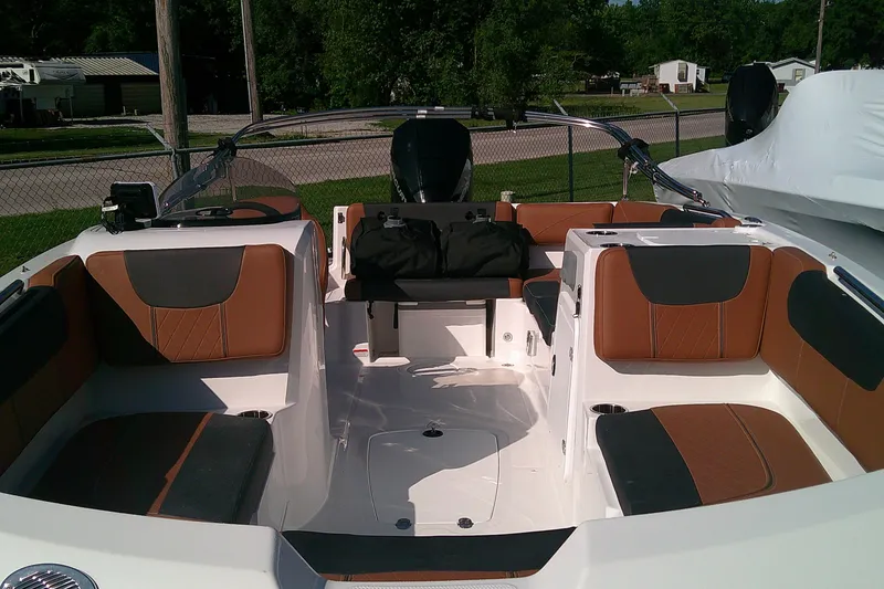 Slide: The Image of 2026 Tahoe 2150 CC boat interior with brown and black seating, parked outdoors. - 2