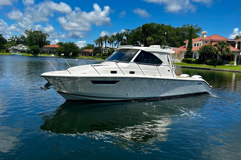 The Image of 2019 Pursuit OS 325 Offshore boat cruising on a serene lake under a clear blue sky. - 0