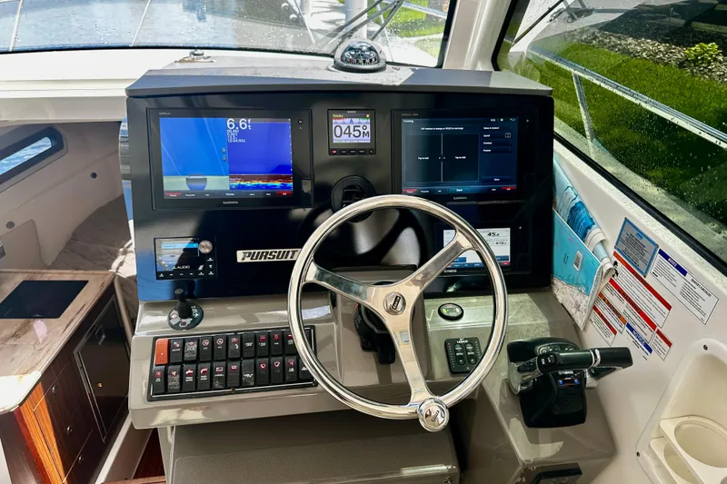Slide: The Image of Helm of 2019 Pursuit OS 325 Offshore boat with advanced navigation displays and controls. - 10