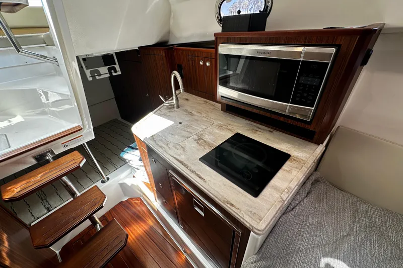 Slide: The Image of 2019 Pursuit OS 325 Offshore boat interior with kitchenette and wooden stairs. - 15