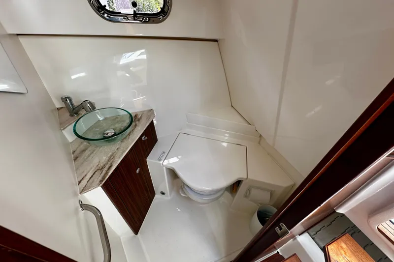 Slide: The Image of 2019 Pursuit OS 325 Offshore boat bathroom with glass sink and compact toilet. - 17