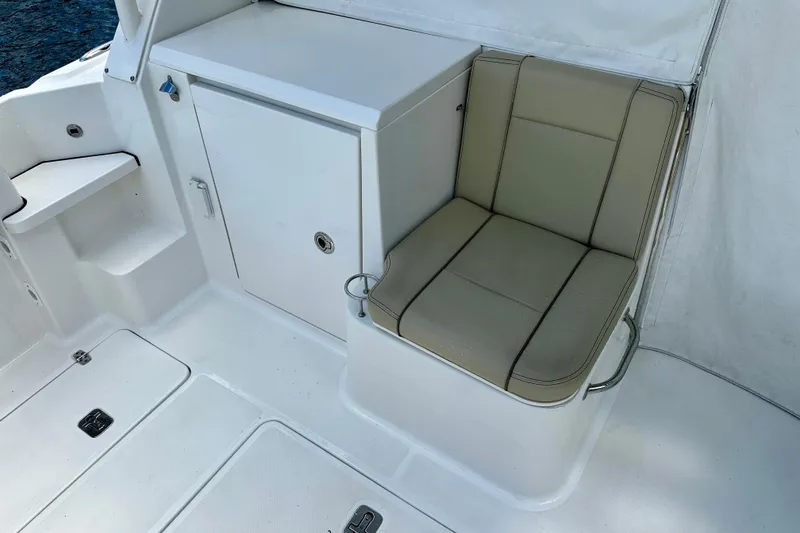 Slide: The Image of 2019 Pursuit OS 325 Offshore boat interior with cushioned seating and storage compartment. - 23